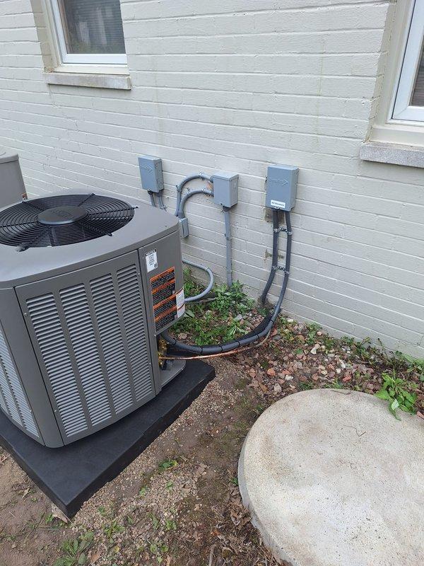Completed installation of 2-ton Lennox air conditioning condenser unit and evaporator coil at residential property. Unit positioned in right yard area on protective pad against exterior wall with white horizontal siding. Installed electrical disconnect boxes, conduit, and refrigerant line connections from outdoor condenser to indoor coil. System reconnected and tested for proper operation following mechanical, electrical, and air conditioning permit requirements.
