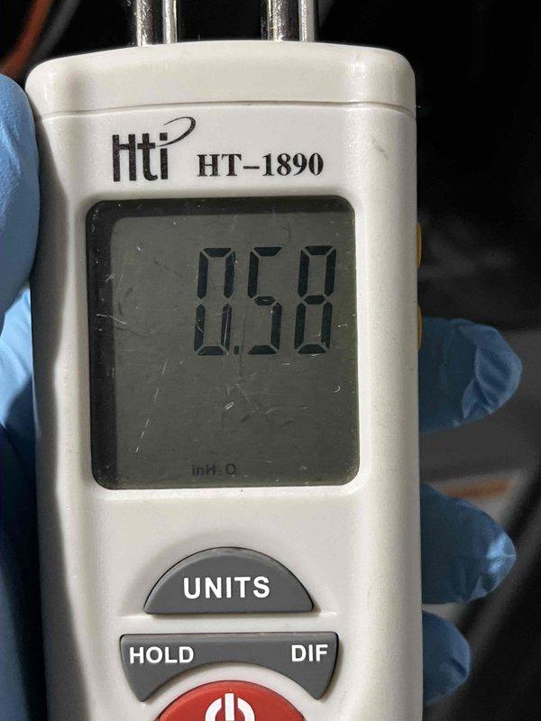 Responded to call for water dripping from AC unit and ductwork at lower level. Inspected recently installed air conditioning system, approximately a few months old. Performed pressure differential testing using digital manometer, recording measurements of 0.61 and 0.58 inches of water column to diagnose drainage issue. Evaluated condensate drain line and ductwork for proper installation and flow. Identified and corrected drainage problem causing water intrusion into living space.