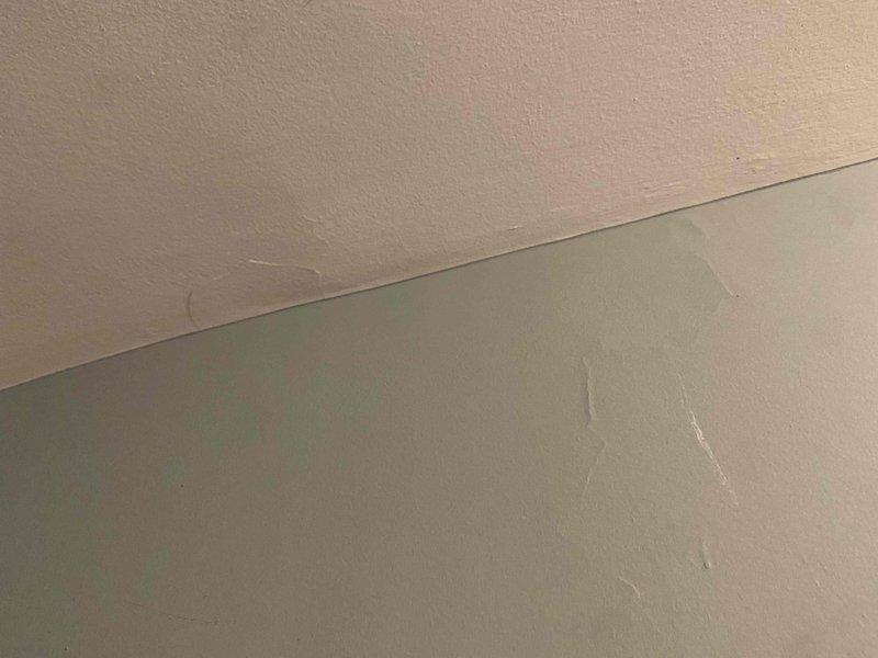 Responded to water leak complaint from attic-mounted air conditioning unit affecting interior ceiling and wall surfaces. Upon inspection, identified active condensate drainage issue from one-year-old system. Located source of leak at primary drain line, found clogged condensate drain causing overflow and water intrusion into living space. Cleared obstruction from drain line using appropriate methods, verified proper drainage flow, and tested system operation to confirm cooling function remained intact. Documented water damage to ceiling and wall surfaces in affected area showing discoloration and moisture staining patterns. Advised property owner of damage extent and recommended monitoring for additional moisture issues. System restored to proper operation with condensate draining correctly.