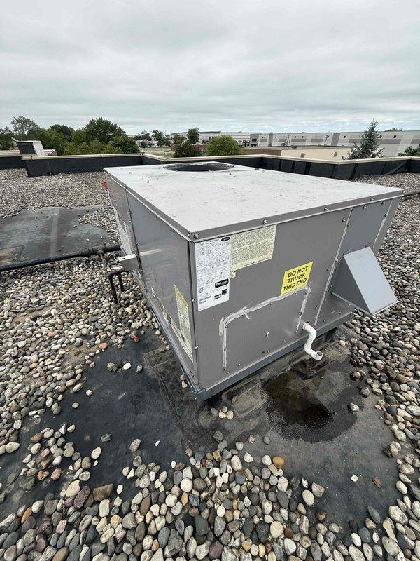 Responded to no cooling complaint on commercial rooftop unit RTU 5. Accessed roof-mounted equipment, inspected blower assembly and motor drive system, verified belt condition and tension on centrifugal fan. Documented unit configuration and operational status with AX42 designation, checked wiring connections and motor mounting. Unit restored to proper cooling operation.