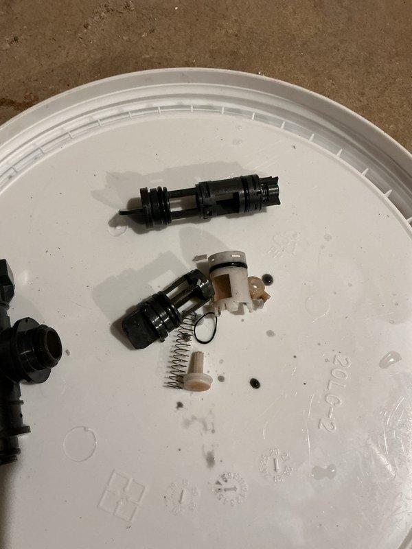 Diagnosed tankless water heater malfunction and identified failed flow sensor and check valve requiring replacement. Disassembled and removed defective components, documented condition with photos showing strainer-type flow sensor with cage assembly and check valve with internal spring mechanism. Ordered replacement parts through vendor with delivery to warehouse; unit temporarily out of service pending parts arrival and installation to restore proper operation.