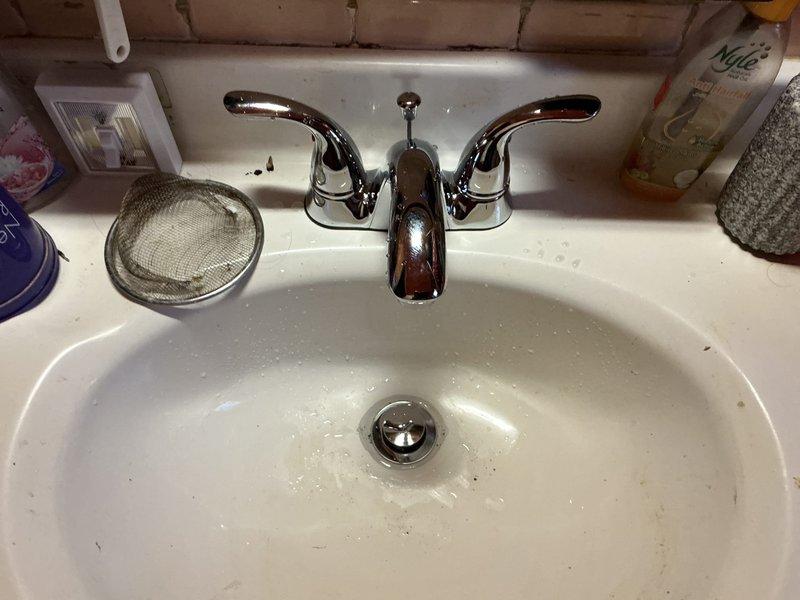 Responded to service call for installation of two bathroom faucets. Successfully removed existing fixtures and installed new chrome two-handle faucets with matching drain assemblies. First installation completed on white oval bathroom sink with proper mounting through three-hole configuration, ensuring secure connections to hot and cold water supply lines. All connections tested for leaks and proper water flow. Second faucet installation performed with same specifications. Both fixtures operational with no leaks detected upon final inspection.