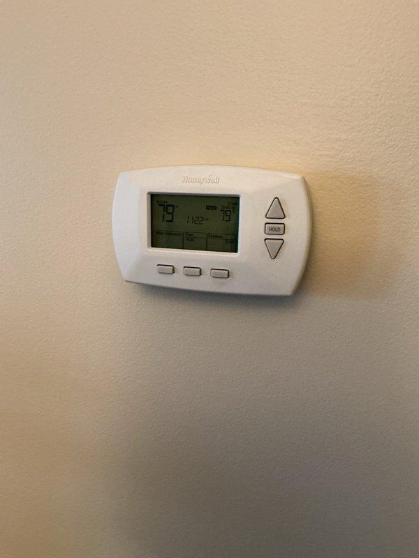 Responded to service call for 3-year-old furnace leaking water from the bottom in basement location. Upon inspection, observed moisture accumulation on concrete floor beneath and around HVAC equipment. Examined condensate drainage system including white PVC piping and drain lines for blockages, improper pitch, or disconnections. Verified thermostat operation showing system actively running at time of inspection. Assessed air handler unit and surrounding components for signs of condensate overflow, clogged drain pan, or compromised drainage pathways that would cause water leakage at base of unit.
