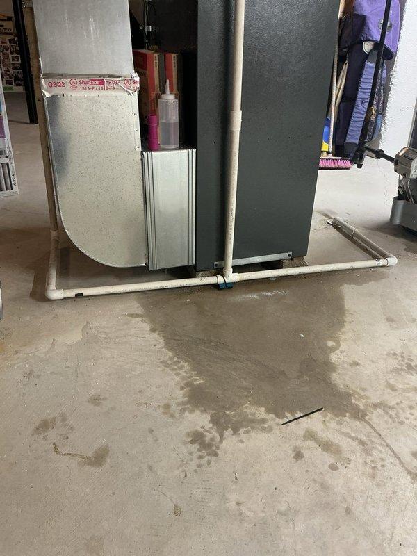 Responded to service call for 3-year-old furnace leaking water from the bottom in basement location. Upon inspection, observed moisture accumulation on concrete floor beneath and around HVAC equipment. Examined condensate drainage system including white PVC piping and drain lines for blockages, improper pitch, or disconnections. Verified thermostat operation showing system actively running at time of inspection. Assessed air handler unit and surrounding components for signs of condensate overflow, clogged drain pan, or compromised drainage pathways that would cause water leakage at base of unit.