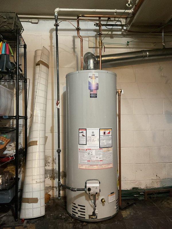 Completed standard installation of 50-gallon tanked water heater in basement utility area. Connected all copper supply lines, gas line with proper fittings, and exhaust venting to ensure code-compliant operation. Unit is fully operational with all safety labels visible and accessible for future reference.