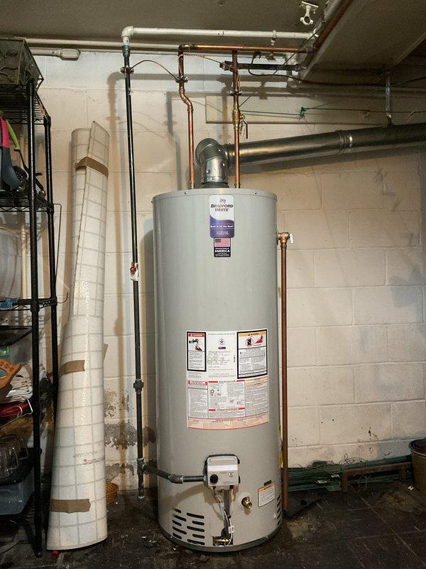 Completed standard installation of 50-gallon tanked water heater in basement utility area. Connected all copper supply lines, gas line with proper fittings, and exhaust venting to ensure code-compliant operation. Unit is fully operational with all safety labels visible and accessible for future reference.