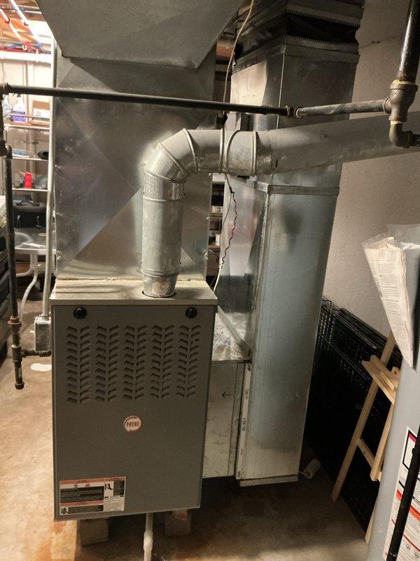 Responded to service call for 19-year-old air conditioning system reported as not cooling. Upon inspection, confirmed outdoor AC unit was non-operational and had reached end of serviceable life. Evaluated existing HVAC system including indoor furnace, ductwork configuration, and air distribution components. Documented current equipment setup with Payne furnace installation, supply plenum, and associated mechanical connections including gas lines and condensate drainage. Provided comprehensive replacement estimate for new cooling system to restore climate control functionality.