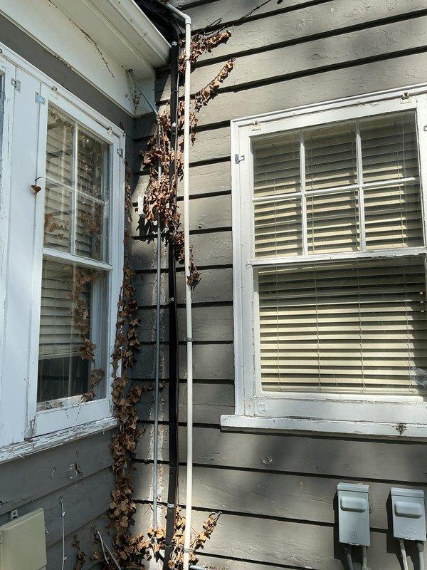 Responded to service call for non-operational five-year-old Carrier AC system providing no cooling to residence. Performed comprehensive system evaluation of both outdoor condensing unit and indoor air handler located in attic space. Assessed existing Lennox air handler installation with associated ductwork, refrigerant lines, and condensate management system. Evaluated exterior condensing unit condition, noting vegetation debris accumulation on refrigerant line set and surrounding infrastructure requiring clearance for proper system operation. Documented current equipment configuration including flexible duct distribution system with Johns Manville insulation and copper refrigerant piping with insulation jacket. Provided detailed estimate for complete HVAC system replacement including new outdoor condensing unit and compatible air handler to restore cooling capacity and system functionality. Captured photographic documentation of existing equipment condition, installation location, an