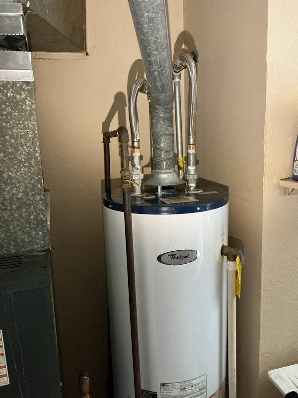 Responded to service call for water heater with pilot light that would not ignite. Upon arrival, inspected Whirlpool tanked water heater unit located in basement utility area alongside HVAC equipment. Performed diagnostic assessment of pilot assembly, thermocouple, and gas supply line. Tested gas valve operation and verified proper venting through existing exhaust system. Cleaned pilot orifice and burner assembly to ensure proper flame characteristics. Checked all copper supply line connections and fittings at top of unit for integrity. Successfully relit pilot light and verified sustained ignition. Tested main burner operation through full heating cycle to confirm proper function. Inspected surrounding area and confirmed adequate clearances per manufacturer specifications. Unit restored to full operational status with pilot remaining lit and burner cycling appropriately.