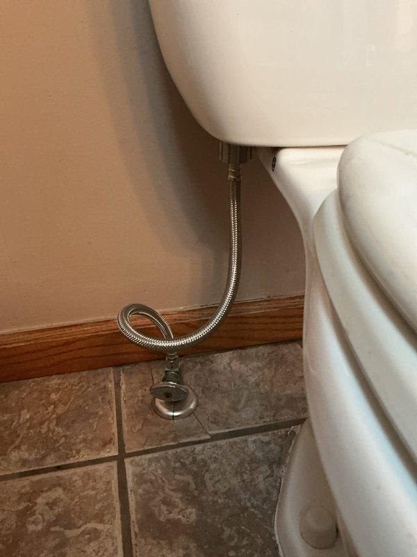 Performed inspection of residential toilet to assess condition and provide repair versus replacement recommendation. Removed tank lid to examine internal flush mechanisms, noting functional black float valve and flush assembly. Observed significant mold and mildew buildup around interior tank rim with dark brown and black staining where lid interfaces with tank body, indicating prolonged moisture exposure and potential seal deterioration. Verified water supply line connection with braided stainless steel flex line and shut-off valve at floor level in proper working condition. Documented toilet condition including ceramic surfaces, two-piece standard design, and overall functionality to provide comprehensive estimate options for repair of existing fixture or complete replacement.