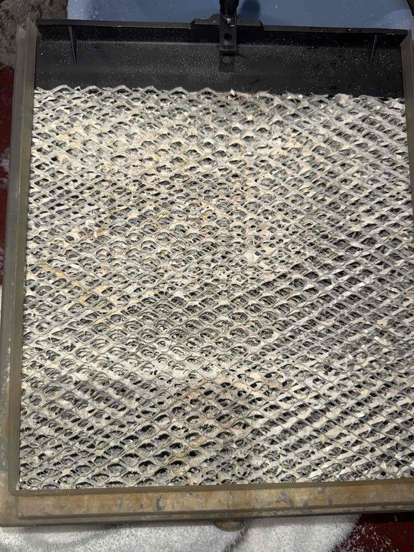 Responded to service call for fluid leaking from 12-year-old furnace located in basement. Upon inspection, identified source of leak as heavily clogged humidifier pad with significant mineral buildup and debris accumulation causing water overflow from humidifier unit. Removed and inspected saturated evaporator pad, which showed extensive contamination and reduced water flow capacity. Replaced soiled humidifier filter pad with new unit, cleared drain pan of accumulated sediment, and verified proper water flow and drainage operation. System tested and returned to normal operation with no further leaking observed.