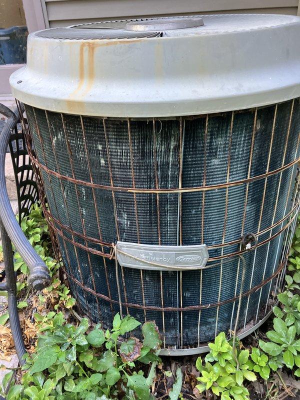 Provided comprehensive replacement estimate for 30+ year old residential HVAC system including natural gas furnace located in crawl space/utility room and outdoor air conditioning condenser unit. Current equipment remains operational but exhibits significant age-related deterioration, with outdoor unit showing extensive weathering, surface staining, and corrosion on protective cage and copper components. Assessed existing installation configuration, electrical connections, refrigerant line routing, and condensate drainage to determine optimal replacement specifications for improved energy efficiency and system reliability.