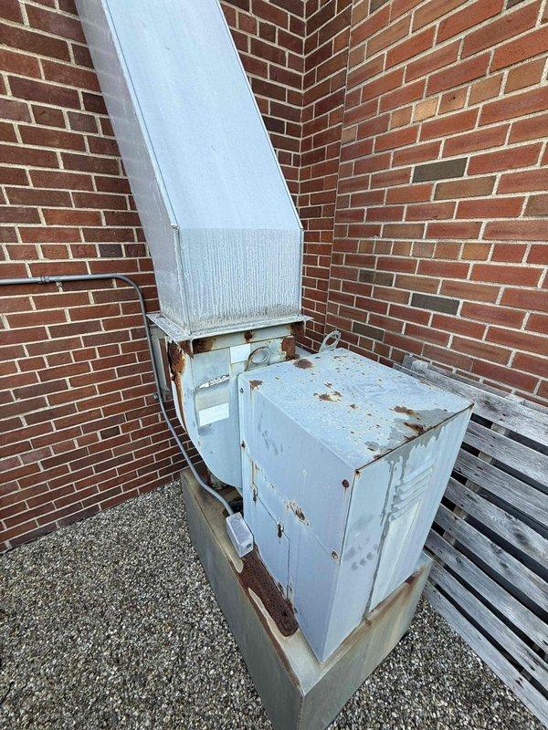 Responded to service call for makeup air unit with missing exterior chimney cap. Upon inspection, located unit on rooftop in southern portion of building and documented existing condition of 20+ year old equipment showing significant weathering, rust deterioration, and paint degradation on metal casing. Unit remains operational and able to cool despite age and exterior corrosion. Took measurements and photographic documentation of chimney opening and overall equipment condition for cap replacement recommendations.