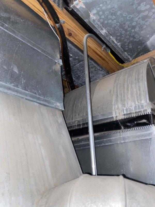 Conducted comprehensive assessment of 20-year-old furnace system located in basement to provide estimate for complete replacement and ductwork installation. Evaluated existing HVAC infrastructure including metal ductwork assembly, plenum condition, and air handling components in confined installation space. Documented current system configuration showing galvanized steel ductwork with visible wear patterns, condensation marking, and dust accumulation consistent with equipment age. Assessed wooden framing members, black flexible ductwork, drain lines, and reflective insulation materials in mechanical space. Photographed existing equipment condition and utility area components including PVC condensate piping and surrounding infrastructure to support replacement specifications. No immediate operational failures or emergency symptoms reported at time of evaluation.