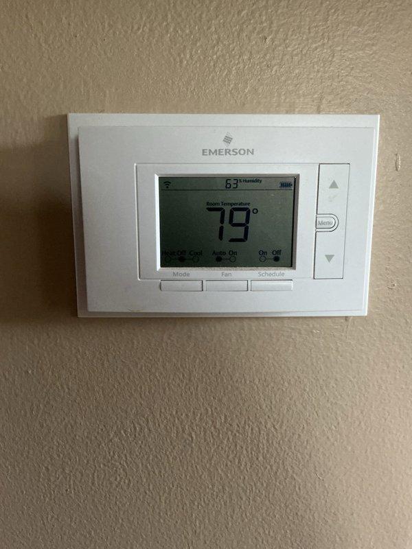 Responded to service call for noisy outdoor compressor unit. Upon arrival, verified system was still operational and maintaining cooling capacity. Inspected Emerson digital thermostat displaying 79°F room temperature with 63% humidity, confirmed proper communication between thermostat and HVAC system. Proceeded to basement to examine furnace and air handler installation. Evaluated electrical connections, ductwork, and PVC condensate drainage system for any issues that could contribute to compressor noise. Photographed thermostat settings and basement equipment configuration for service records. System remained functional throughout inspection with heating and cooling capabilities intact.
