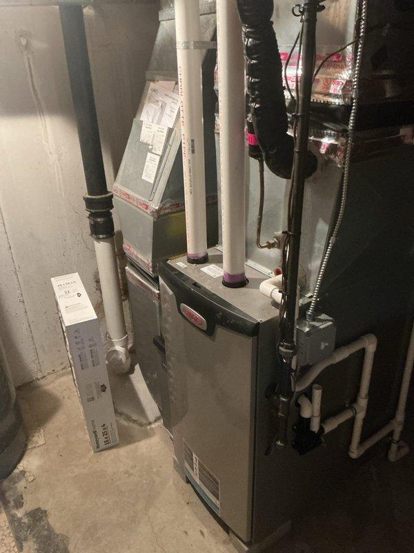 Responded to service call for noisy outdoor compressor unit. Upon arrival, verified system was still operational and maintaining cooling capacity. Inspected Emerson digital thermostat displaying 79°F room temperature with 63% humidity, confirmed proper communication between thermostat and HVAC system. Proceeded to basement to examine furnace and air handler installation. Evaluated electrical connections, ductwork, and PVC condensate drainage system for any issues that could contribute to compressor noise. Photographed thermostat settings and basement equipment configuration for service records. System remained functional throughout inspection with heating and cooling capabilities intact.