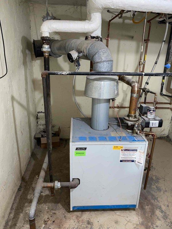 Performed comprehensive assessment of existing 10+ year old natural gas boiler located in basement for replacement estimate. Unit is currently operational but has reached end of expected service life. Evaluated existing infrastructure including galvanized and copper piping connections, PVC venting system, and electrical components to determine replacement specifications and any necessary modifications for new equipment installation.