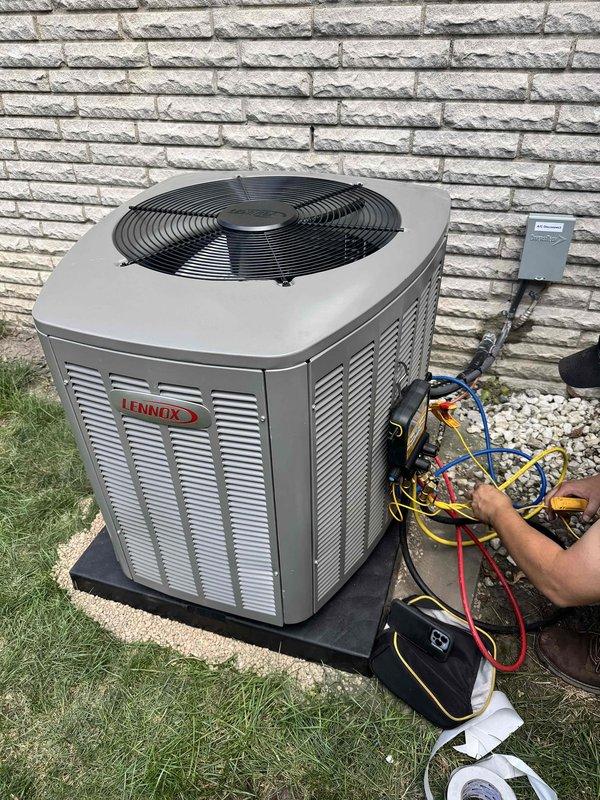 Completed installation of 2.5-ton Lennox air conditioning condenser unit with matching evaporator coil at rear location of residential property. Unit was positioned on concrete pad against exterior brick wall with proper clearances maintained for service access and airflow. Connected refrigerant lines, electrical disconnect, and performed system startup with manifold gauge testing to verify proper refrigerant pressures and system operation. Mechanical and electrical permits were obtained prior to installation per local code requirements.