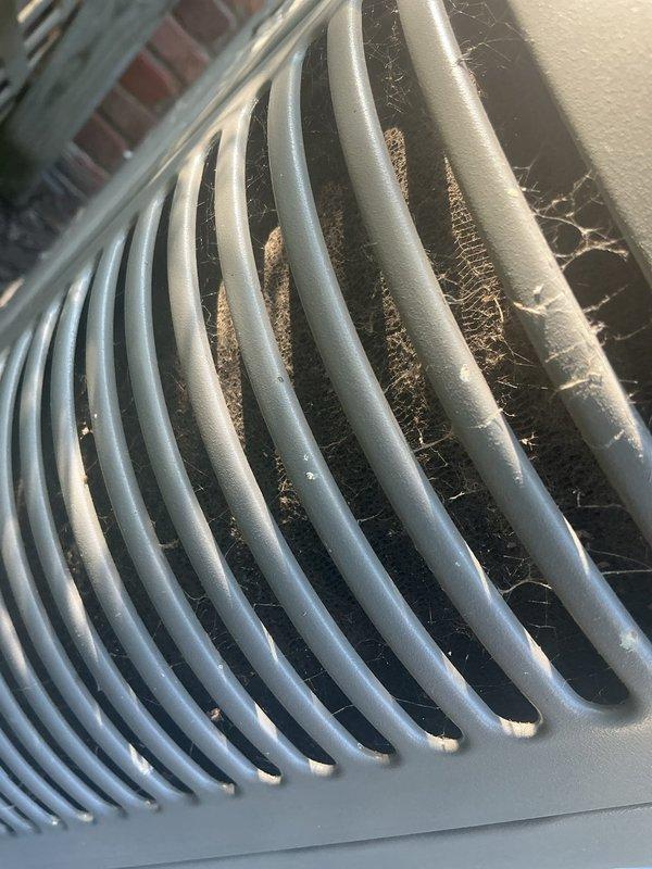 Responded to no cooling complaint on one-year-old AC system located in attic. Upon inspection, found outdoor condenser unit with heavily restricted airflow due to significant dust and debris accumulation on exterior grille and condenser coils. Cleaned condenser coils and fan grille, removed debris buildup from all exterior surfaces, and verified proper airflow restoration. System tested and confirmed cooling operation restored to normal parameters.