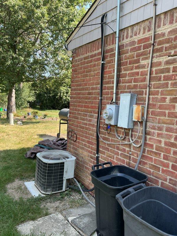 Provided estimate for complete HVAC system replacement including non-operational air conditioning unit and natural gas furnace, both located in attic with condenser positioned on exterior concrete pad. Existing equipment exceeded 20-year service life and required full replacement to restore cooling and heating functionality. Documented current electrical service configuration including meter, disconnect panel, and conduit routing along exterior brick wall for proper system sizing and installation planning.