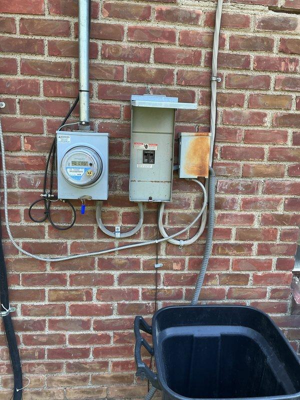 Provided estimate for complete HVAC system replacement including non-operational air conditioning unit and natural gas furnace, both located in attic with condenser positioned on exterior concrete pad. Existing equipment exceeded 20-year service life and required full replacement to restore cooling and heating functionality. Documented current electrical service configuration including meter, disconnect panel, and conduit routing along exterior brick wall for proper system sizing and installation planning.