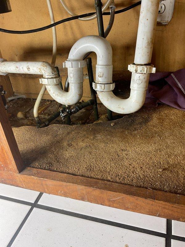 Responded to a plumbing service call for a residential kitchen and bathroom sink system. Upon inspection, found aging PVC drain assemblies under the bathroom sink cabinet with visible mineral deposits, discoloration, and worn coupling connections. Performed diagnostic testing of the kitchen sink faucet and drainage system, confirmed proper water flow and pressure at the two-handle chrome faucet assembly. Documented existing plumbing infrastructure conditions including dual P-trap configurations, verified all drain connections for proper sealing, and assessed the overall functionality of both fixture assemblies to ensure code compliance and operational integrity.