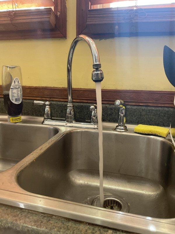 Responded to a plumbing service call for a residential kitchen and bathroom sink system. Upon inspection, found aging PVC drain assemblies under the bathroom sink cabinet with visible mineral deposits, discoloration, and worn coupling connections. Performed diagnostic testing of the kitchen sink faucet and drainage system, confirmed proper water flow and pressure at the two-handle chrome faucet assembly. Documented existing plumbing infrastructure conditions including dual P-trap configurations, verified all drain connections for proper sealing, and assessed the overall functionality of both fixture assemblies to ensure code compliance and operational integrity.