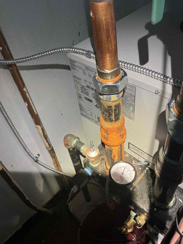 Responded to callback for boiler system with reported leak and improper wiring concerns on equipment under one year old. Inspected boiler installation in basement, verified all electrical connections per manufacturer specifications, and examined copper piping connections at pump assembly and water heater interface. Straightened and repositioned copper supply line that had been previously installed at improper angle, ensuring proper pitch and support. Tightened compression fittings at brass connections, tested system for leaks under operating pressure, and confirmed no active water discharge from piping or pump assembly. Verified circulator pump operation and pressure gauge readings within normal parameters. System tested and operational with no leaks detected at time of departure.