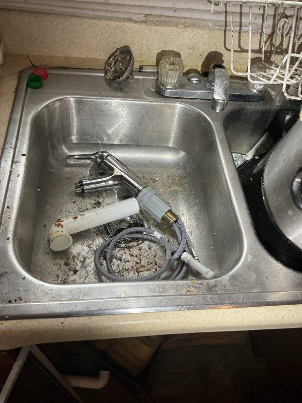 Conducted comprehensive plumbing assessment for drain pipe replacement and repair at residential property involving kitchen sink, bathroom tub, and toilet systems. Inspected dual-basin stainless steel kitchen sink with partially disassembled faucet assembly, noting deteriorated condition with significant mineral deposits and drainage concerns. Evaluated under-sink plumbing configuration including white PVC drain assembly with chrome drain baskets, vertical drain pipe connections, flexible hoses, and inline water filtration component. Documented existing infrastructure condition, wear patterns, and necessary repairs to provide accurate estimate for drain line replacement and fixture restoration across multiple bathroom and kitchen locations.