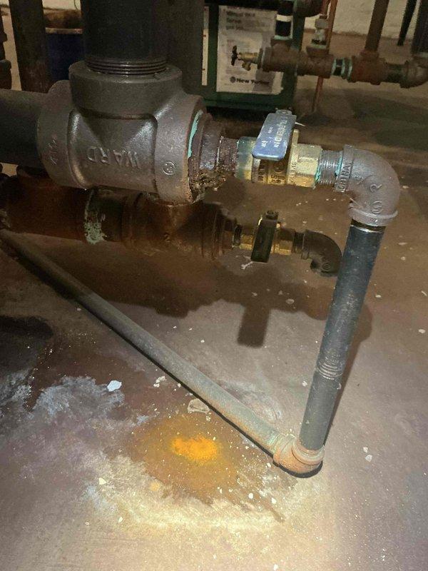 Completed return visit to address leaking and corroded piping on 5-year-old boiler system located in basement. Replaced deteriorated galvanized steel pipe sections showing active leaks and rust damage with new components including two 3/4" bushings, 3/4" shut-off valve, and multiple 3/4" nipples. Removed heavily corroded brass fittings and reinstalled plumbing assembly with proper threading and sealing to eliminate water intrusion. System tested under pressure following repairs with no leaks detected. Boiler remained operational throughout service and continues providing heat. Floor area beneath repaired section showed evidence of previous water damage from leaking pipes, which has now been resolved with replacement components.