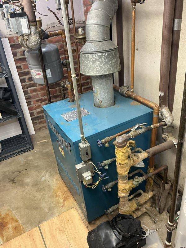 Completed comprehensive Gold level seasonal maintenance on a 10-year-old residential boiler system in basement location. Performed full system tune-up including inspection of all major components, burner assembly, heat exchanger, and flue venting. Verified proper operation of combustion air intake and exhaust ventilation through galvanized vent piping. Inspected and tested expansion tank mounting and pressure settings. Examined all copper and brass supply and return piping connections for leaks or deterioration, noting insulation condition on hot water lines. Tested thermostat functionality and verified proper communication between control system and boiler unit. Checked gas connections, electrical components, and safety controls. Measured and documented operating pressures and temperatures to ensure system is performing within manufacturer specifications. Cleaned burner components and adjusted for optimal combustion efficiency. Verified proper condensate drainage and inspected all vis