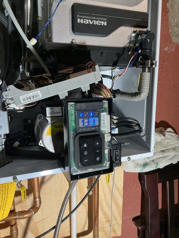 Completed repair service on Navien tankless water heater system. Retrieved replacement part from Munch Supply Madison Heights under PO#1363955, installed component, and verified proper system operation with digital control panel displaying normal readings.
