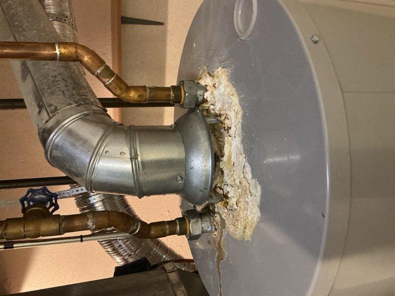 Responded to service call for water leaking from furnace in basement with suspected condensate pump failure. Upon inspection, discovered significant water damage and mineral deposits on water heater tank and surrounding pipe connections, indicating long-term leak issues at tank junction points. Assessed HVAC system and prepared for customer-supplied Nest thermostat installation to replace existing unit.
