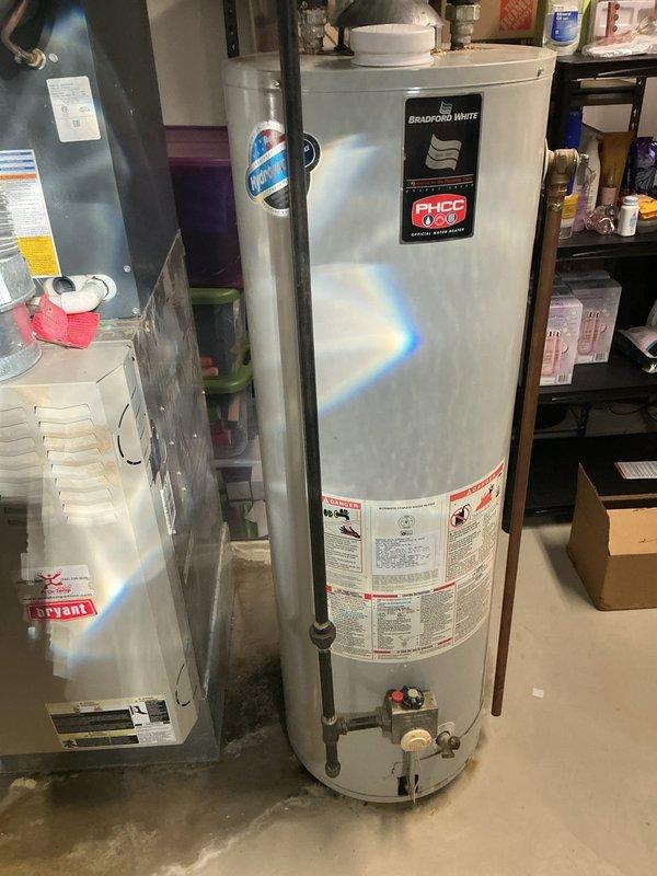 Responded to a water heater failure in a 22-year-old residential property where the existing unit had been leaking from the bottom for seven days. Removed and properly disposed of the failed water heater, then installed a new 40-gallon Bradford White tanked water heater in the basement mechanical room. Installation included connecting copper supply lines to the top of the unit, installing a drip pan beneath the water heater for leak protection, and ensuring all plumbing connections met code requirements. Verified proper operation of the new unit and confirmed no active leaks at supply connections or drain valve.