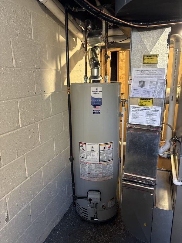 Successfully completed installation of 2-ton air conditioning system with evaporator coil and 40-gallon standard water heater in rear utility room. All refrigerant lines, condensate drainage, and electrical connections were properly installed and tested. Mechanical and electrical permits were obtained prior to installation, and existing thermostat was upgraded to Sensi programmable unit. System was commissioned, verified for proper operation, and customer qualified for available utility rebates from Consumers Energy and DTE.