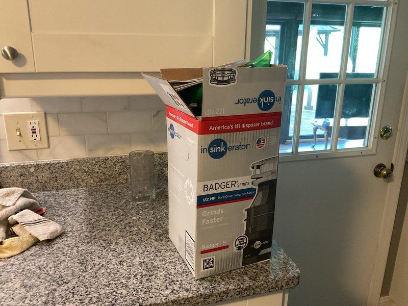 Completed installation of InSinkErator Badger 1/2 HP garbage disposal unit at kitchen sink in 1975-built residence. Removed existing disposal system, mounted new Badger series unit to sink drain assembly, connected white PVC drain piping with P-trap configuration, and secured dishwasher drain line to disposal inlet. Installed electrical connections, tested unit operation for proper grinding function and verified all plumbing connections were leak-free. Positioned catch basin beneath installation during work and ensured all shut-off valves were operational.