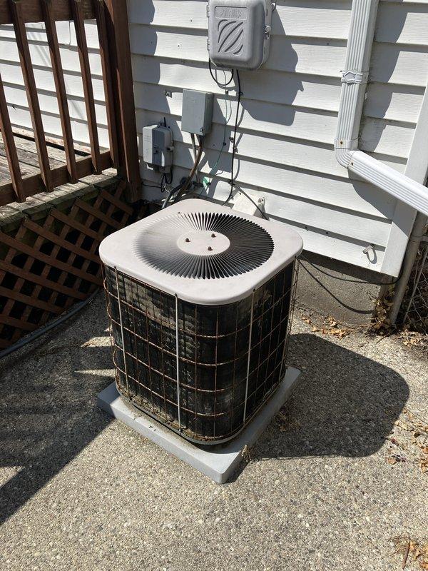 Responded to service call for AC unit leaking inside the house with a 10-year-old system located in the basement. Upon inspection, discovered the system had low refrigerant charge and identified a cracked eyelet on the heat exchanger. Documented existing electrical panel configuration and outdoor condenser unit condition with photographs for estimate purposes.