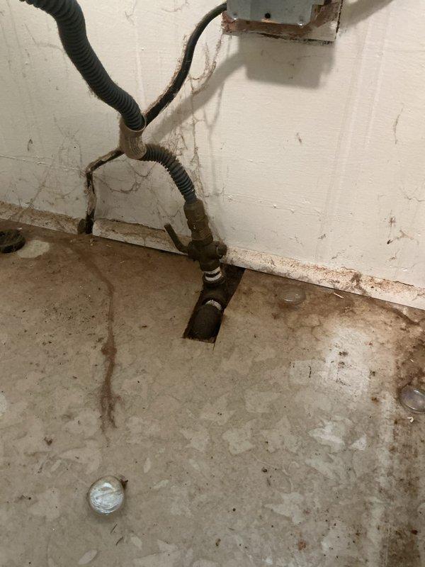 Conducted on-site assessment for converting existing gas line service to electrical supply for kitchen stove installation. Evaluated current gas piping infrastructure in basement utility area, including corroded gas supply line with brass shutoff valve and flexible connectors. Documented existing conditions including aged piping system, floor penetrations, and proximity to electrical junction box to determine scope of work required for safe gas line capping and new electrical circuit installation.