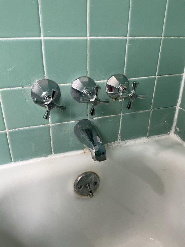 Responded to service call for leaking shower valve in vintage three-handle tub and shower configuration. Upon inspection, identified failed valve cartridge with significant mineral buildup, corroded O-rings, and worn seals causing water seepage. Shut off water supply, removed defective valve stem assembly from wall-mounted fixture, and documented heavy calcium deposits and deterioration on internal components. Replaced faulty cartridge with new unit, installed fresh O-rings and seals, reassembled valve assembly, and restored water supply. Tested all three handles for proper operation and verified complete elimination of leak.