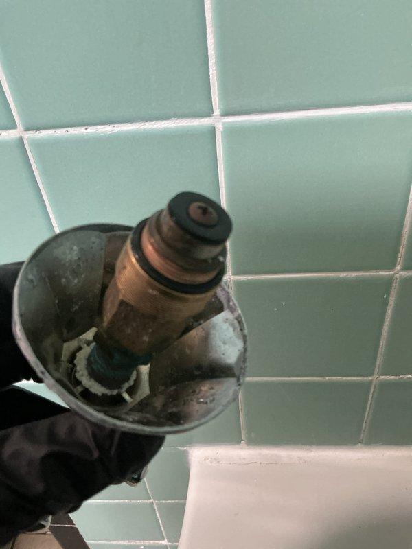 Responded to service call for leaking shower valve in vintage three-handle tub and shower configuration. Upon inspection, identified failed valve cartridge with significant mineral buildup, corroded O-rings, and worn seals causing water seepage. Shut off water supply, removed defective valve stem assembly from wall-mounted fixture, and documented heavy calcium deposits and deterioration on internal components. Replaced faulty cartridge with new unit, installed fresh O-rings and seals, reassembled valve assembly, and restored water supply. Tested all three handles for proper operation and verified complete elimination of leak.