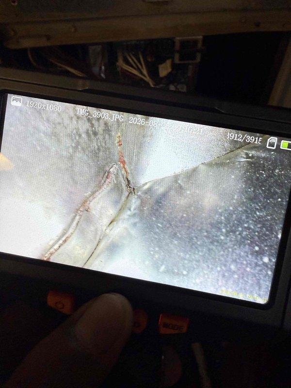 Responded to no cooling complaint on 10+ year old residential air conditioning system with basement evaporator coil location. Upon inspection, discovered severely cracked and deteriorated evaporator coil with visible structural damage and rust staining along fracture lines, indicating refrigerant leak and complete coil failure. Documented coil damage using inspection camera equipment. External examination of outdoor condensing unit revealed significant weathering with peeling exterior coating, debris accumulation around base, and exposed refrigerant lines with damaged insulation. Unit showed signs of extended outdoor exposure and lack of maintenance. Advised homeowner that evaporator coil replacement is required to restore cooling function, and recommended full system evaluation given age of equipment and deteriorated condition of both indoor and outdoor components.