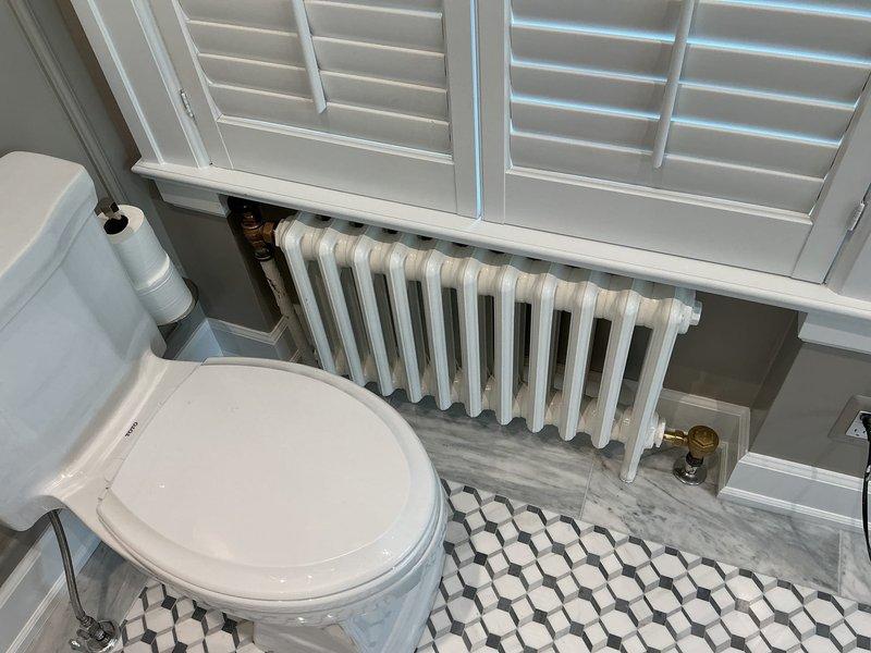 Replaced failed steam traps on cast-iron radiator system in bathroom with 1/2" steam traps sourced from hydronics supply in Ferndale under specified purchase order. Serviced radiator heating unit beneath window, addressing trap failures to restore proper steam heating function and system efficiency.
