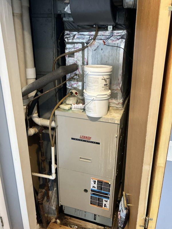 Completed on-site evaluation of 20-year-old Lennox furnace located in utility closet for replacement estimate. Unit currently operational with no reported symptoms or functional issues. Documented existing installation including vertical furnace configuration, copper refrigerant lines with foam insulation, PVC condensate drainage, and ductwork within confined mechanical space. Photographed equipment specifications, clearances, and surrounding infrastructure to provide accurate replacement recommendations and ensure proper sizing for new system installation.
