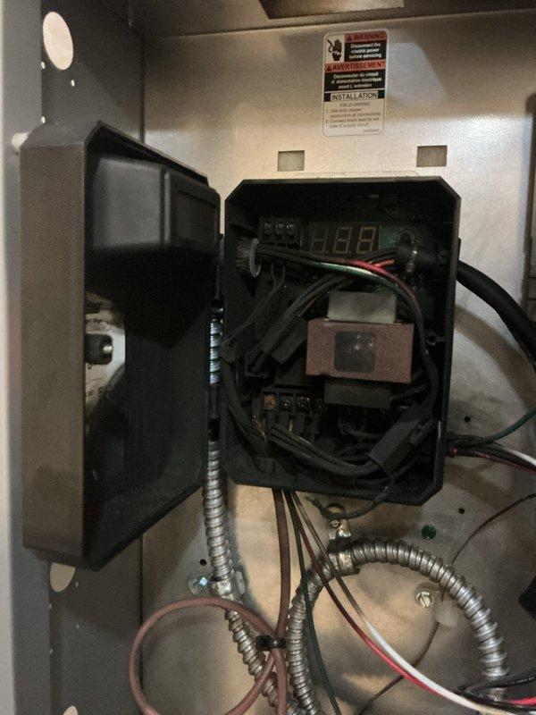 Responded to service call for boiler with control board damaged during previous electrical storm. Upon inspection in basement, confirmed control board was non-functional with visible damage to internal electrical components. Documented existing wiring configuration and electrical connections via photographs showing digital display, transformer assembly, and associated control wiring. Assessed replacement requirements for damaged control board and hydrostat component. Ordered replacement hydrostat under PO 1364849-001 for next-day delivery to shop. System remains offline pending arrival and installation of replacement parts.