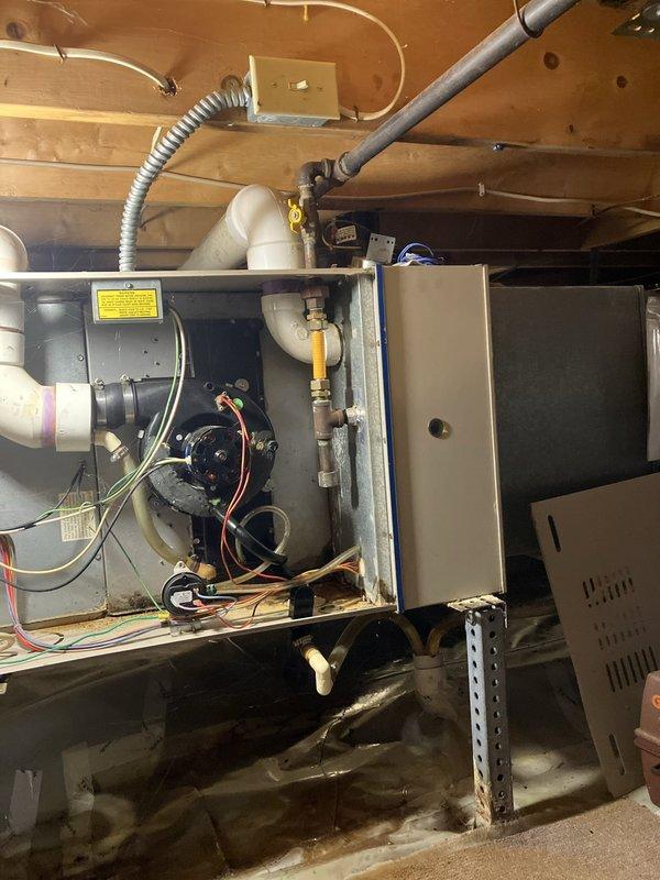 Conducted comprehensive evaluation of 16-year-old air conditioning system for replacement estimate. Inspected outdoor condensing unit on east side of property and assessed indoor air handler components located in crawl space, including blower motor assembly, electrical connections, gas line connections, and ductwork integration with existing furnace system. Documented current system configuration with photographs showing internal mechanical components, PVC condensate drainage, flexible conduit, metal ductwork, and elevated equipment mounting on support brackets with drain pan positioned below unit for proper condensate management.