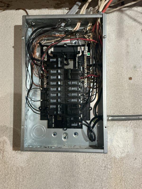 Completed comprehensive whole home electrical inspection in response to reported flickering lights and exposed wiring at the main electrical panel. Performed thorough examination of the residential circuit breaker panel, which contained two vertical rows of standard toggle-style breakers with multiple conductors including black, white, red, and copper-colored wires. Inspected all wire connections at breakers and bus bars, verifying proper terminations and routing throughout the panel. Evaluated exterior electrical service entrance including overhead utility connection, conduit run, meter base, and associated junction boxes mounted on brick exterior wall. Assessed overall electrical system condition, wire organization, and panel installation to identify any safety concerns or code violations. Documented panel configuration and exterior service components with photographs for reference. All findings and recommendations were discussed with homeowner upon completion of inspection.