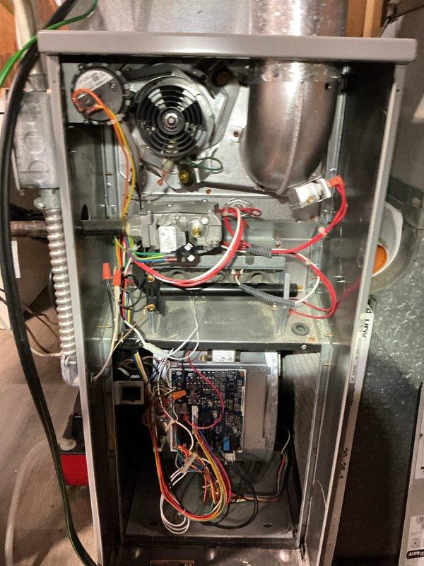Completed comprehensive tune-up and inspection on 10+ year old HVAC system including basement-installed gas furnace and outdoor air conditioning condenser unit. Performed thorough examination of furnace interior components including blower motor assembly, gas valve connections, electrical control board, and all associated wiring harnesses. Verified proper operation of all safety controls and electrical connections throughout the system. Inspected outdoor condenser unit positioned on concrete pad adjacent to building foundation, checking refrigerant lines, electrical disconnect, conduit connections, and fan operation. Confirmed adequate clearance around outdoor unit and verified secure mounting on concrete slab. All components found to be functioning within normal operating parameters with organized wiring and proper installations maintained throughout both heating and cooling systems.