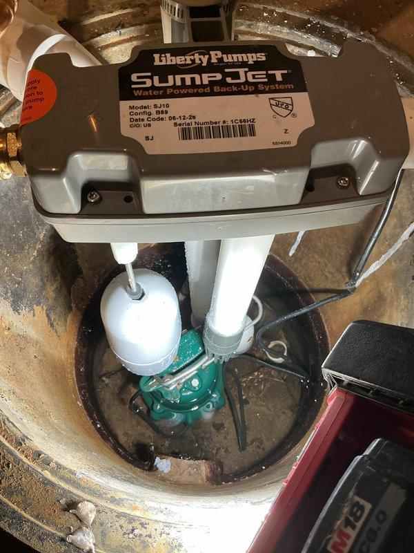 Responded to warranty callback for water backup issue following recent installation of Liberty Pumps Sump Jet water-powered backup sump pump system (Model S-110). Upon arrival, found significant basement flooding with standing water across concrete floor. Inspected sump pit installation and identified malfunction in water-powered backup system causing discharge failure. Diagnosed improper operation of backup pump mechanism, resulting in water overflow from pit during primary pump cycle. Corrected installation deficiencies, tested both primary and water-powered backup systems for proper operation, and verified adequate discharge flow. Confirmed sump pit water level maintained properly with no further backup or overflow conditions.