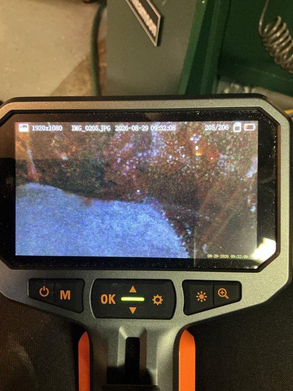 Responded to service call for reported boiler leak on 10-year-old unit located in basement. Upon inspection, identified active leak at threaded pipe connection near boiler manifold assembly. Utilized borescope camera to perform internal inspection of heat exchanger, revealing significant corrosion and scale buildup on interior surfaces. Documented findings with photographic evidence showing deteriorated condition of internal components and compromised pipe fittings. Tagged affected plumbing connections and advised on necessary repairs to address both the immediate leak and underlying corrosion issues within the heat exchanger.
