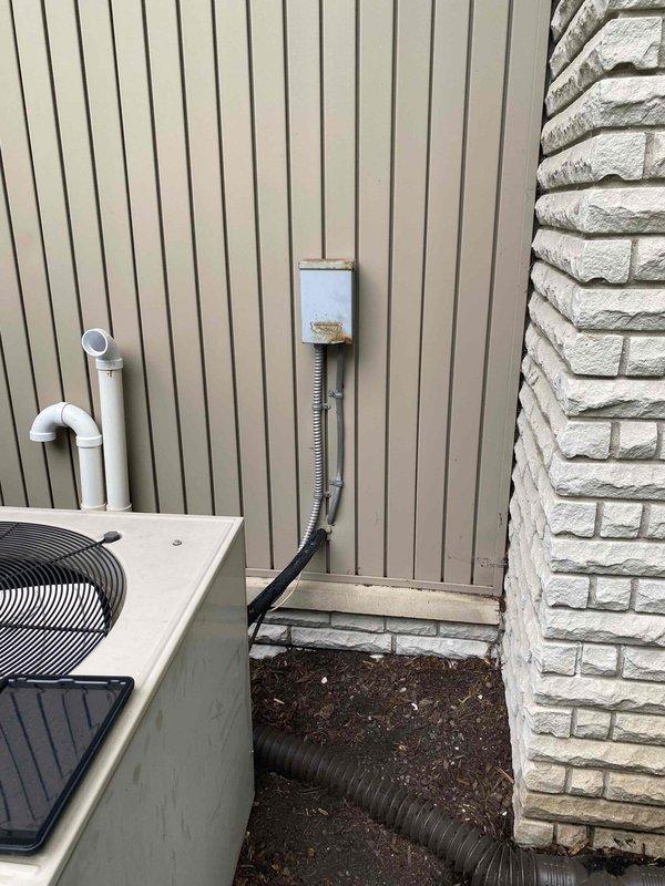 Completed comprehensive HVAC inspection and assessment for air conditioning system replacement on residential property with 20+ year old equipment. Evaluated exterior condenser unit with associated refrigerant lines, condensate drainage, and electrical disconnect components, as well as basement-located furnace and water heater configuration to provide accurate replacement estimate. Documented existing system condition through photographic records showing current equipment placement, utility connections, and spatial considerations for future equipment installation.